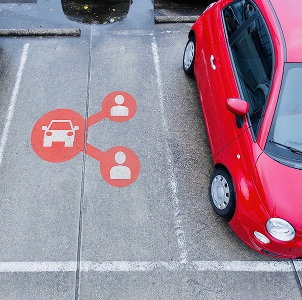 Fototo van een rode elektrische deelauto op een parkeerplaats